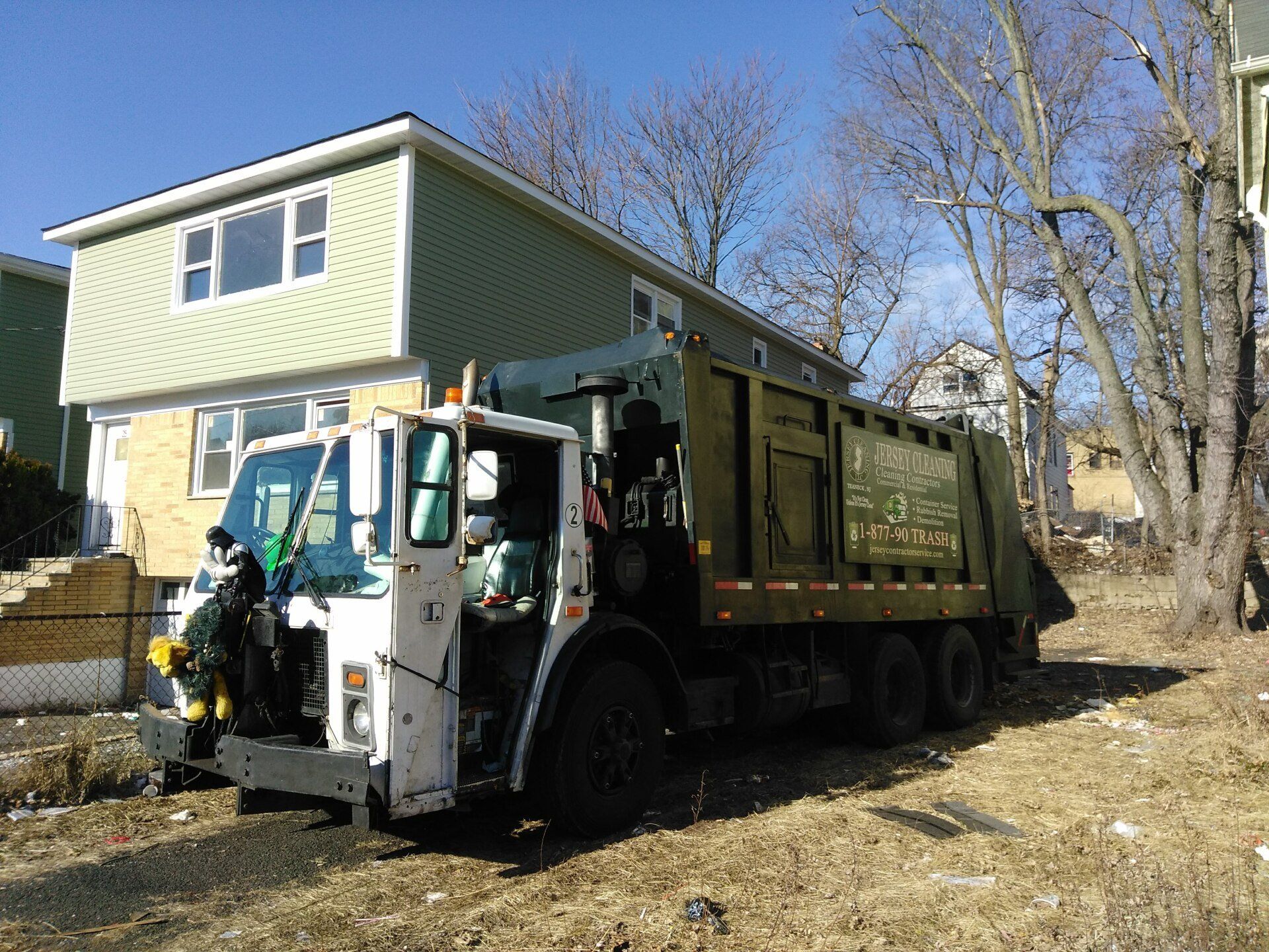 A Jersey Cleaning garbage truck is parked in front of a house.