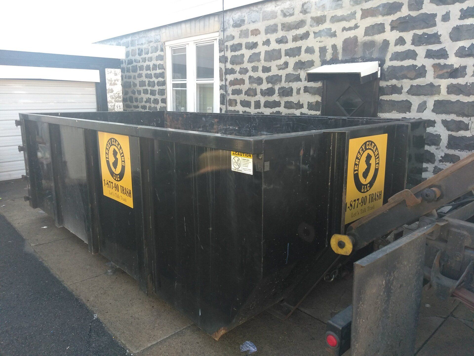 A black Jersey Cleaning dumpster