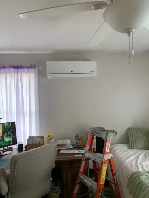 Home office/bedroom with a desk, monitor, bed, ceiling fan, and a ladder in the center.