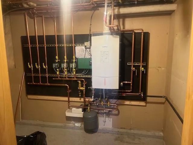 Wall-mounted boiler with copper pipes and valves in a utility room.