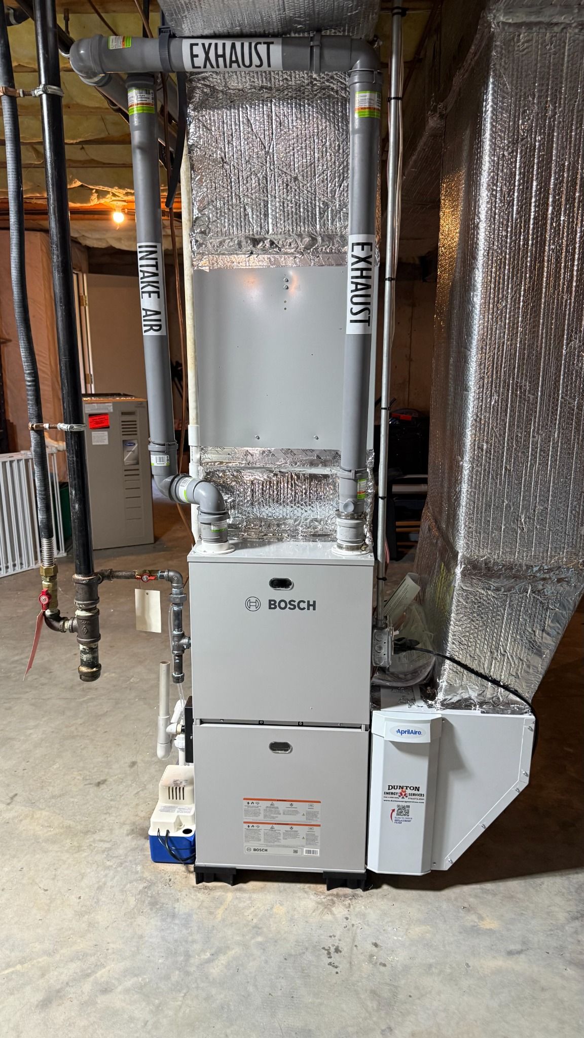 Bosch furnace in an unfinished basement with exposed ducts and insulation