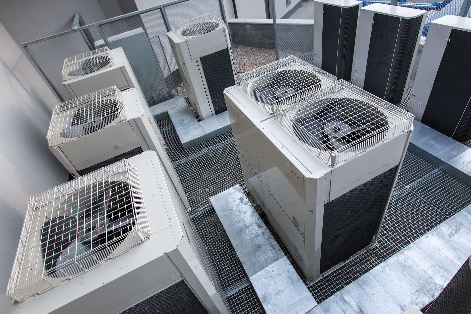 Rooftop view of multiple HVAC units with large fans and metal grates on a building roof