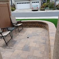 A patio with chairs and a wall in front of a house.