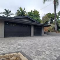 A house with two garage doors and a brick driveway.