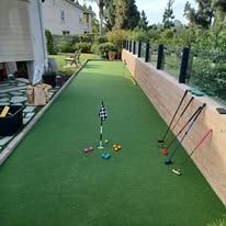 A putting green with golf clubs and balls on it.