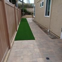 A brick walkway with a green carpet leading to a house.