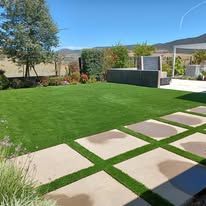 A backyard with a lush green lawn and a patio.