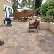 A patio with a table and chairs and an umbrella in front of a house.