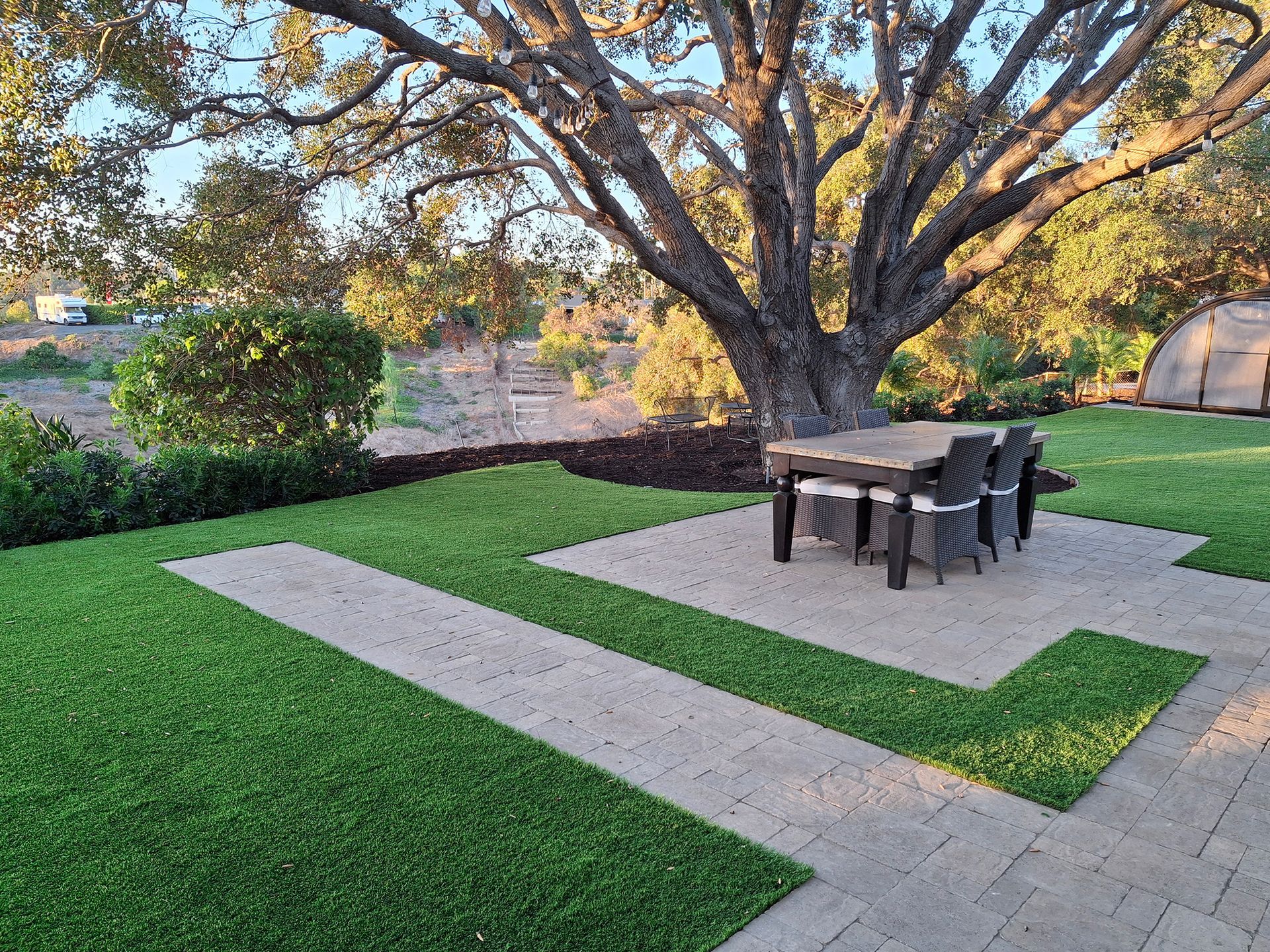A patio with a table and chairs under a tree.