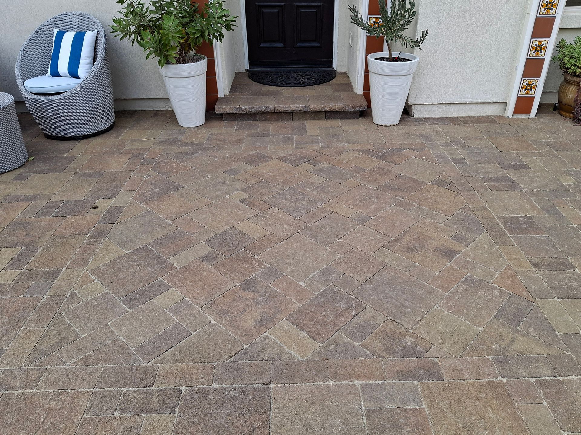A patio with chairs and potted plants in front of a house