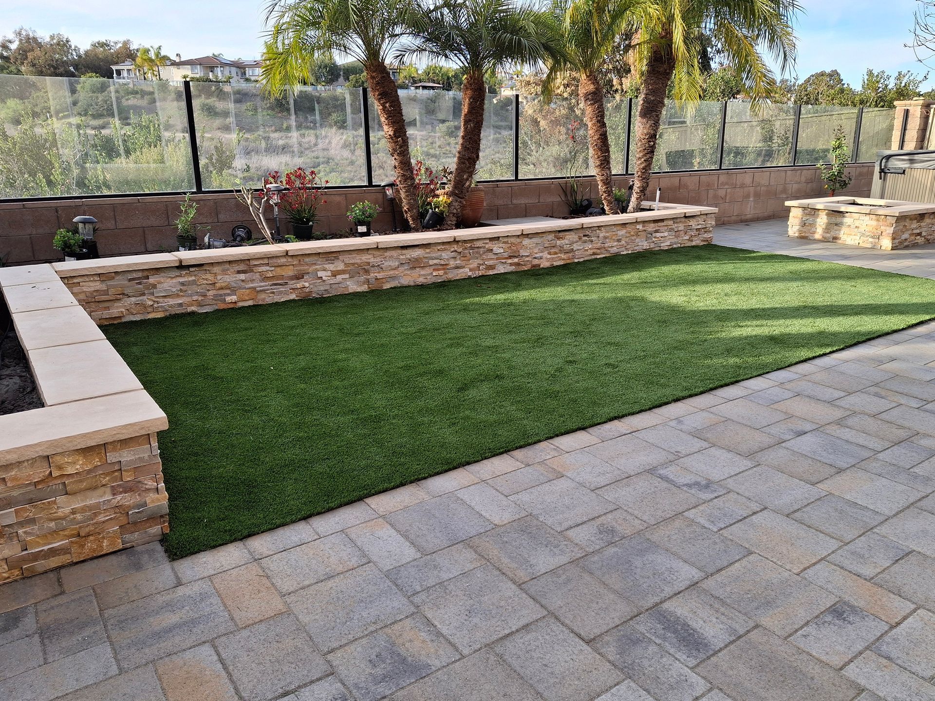 A patio with a lush green lawn and a stone wall.