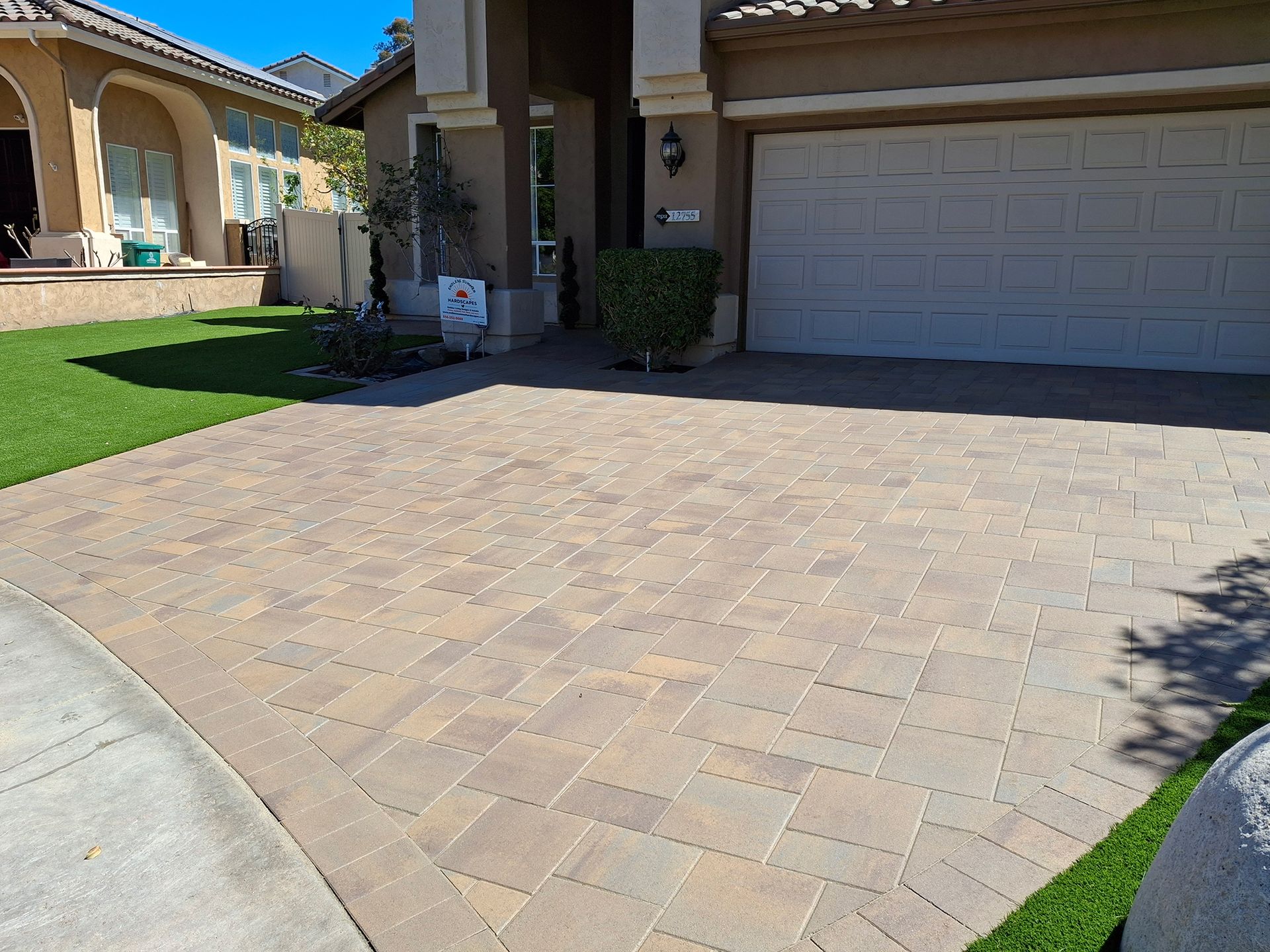 A brick driveway in front of a house with a garage door.