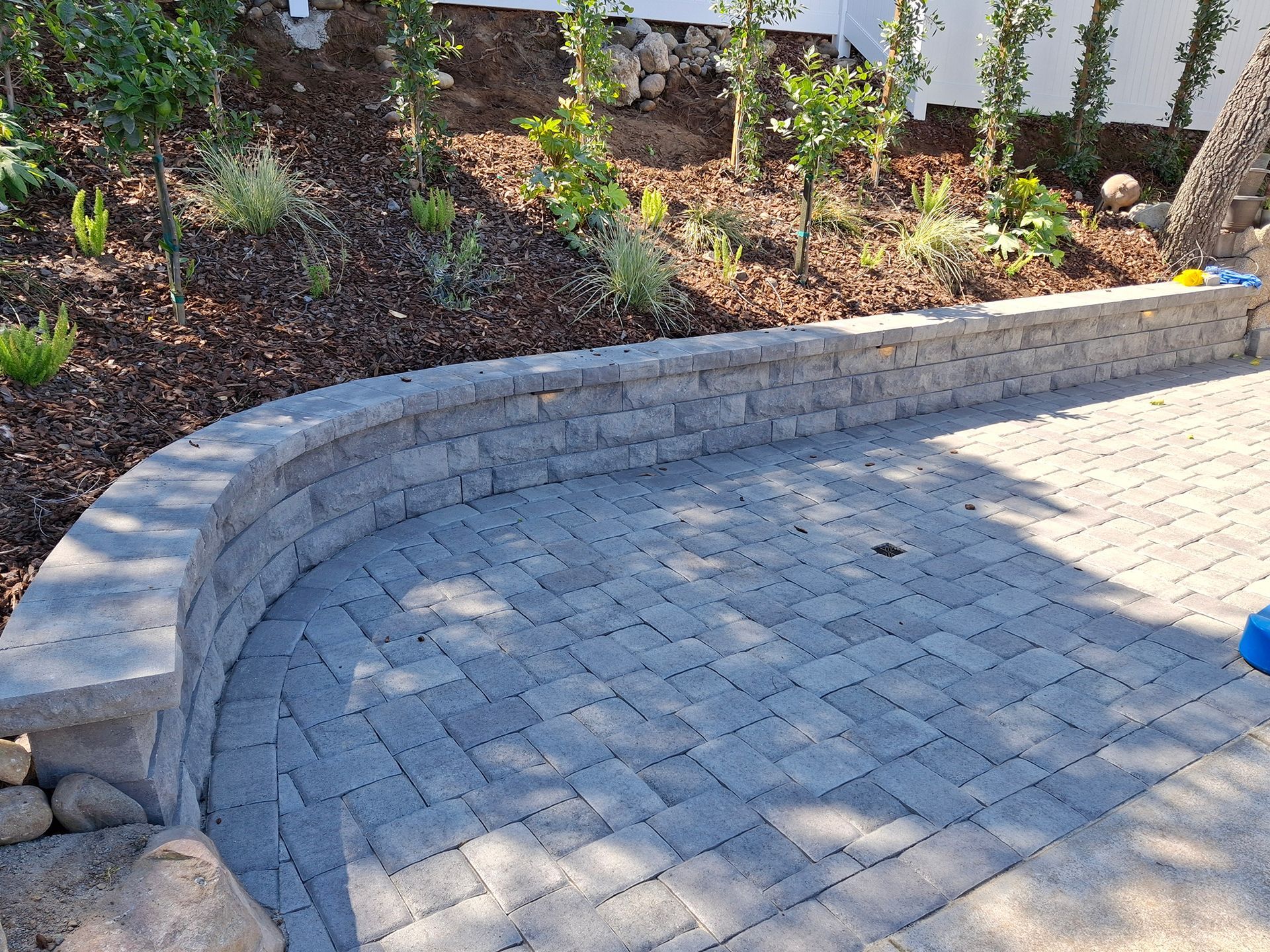 A brick wall is surrounding a patio with a brick walkway.