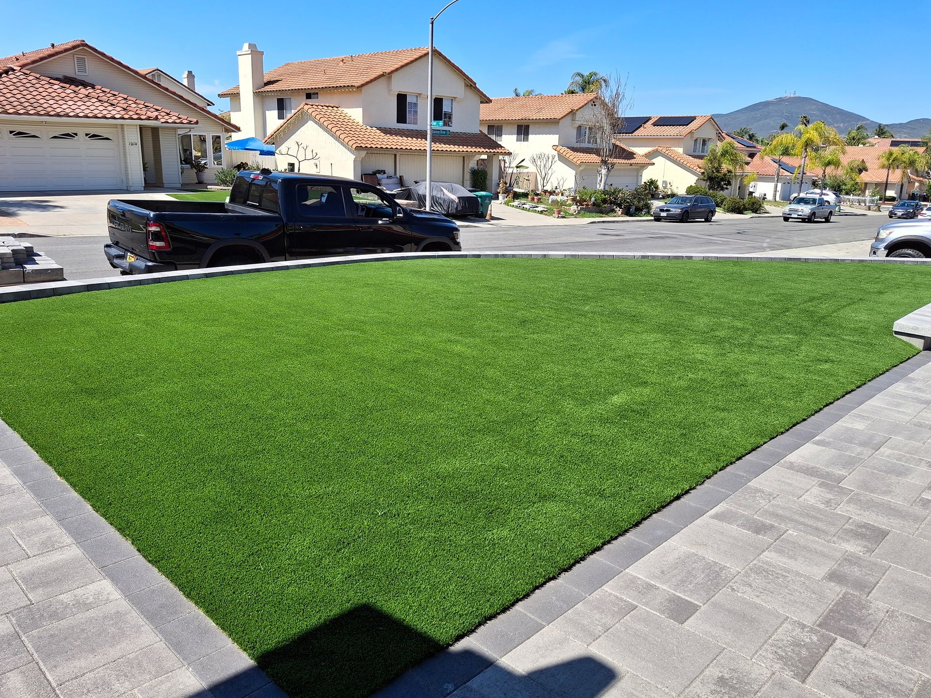 A truck is parked in the grass in front of a house.