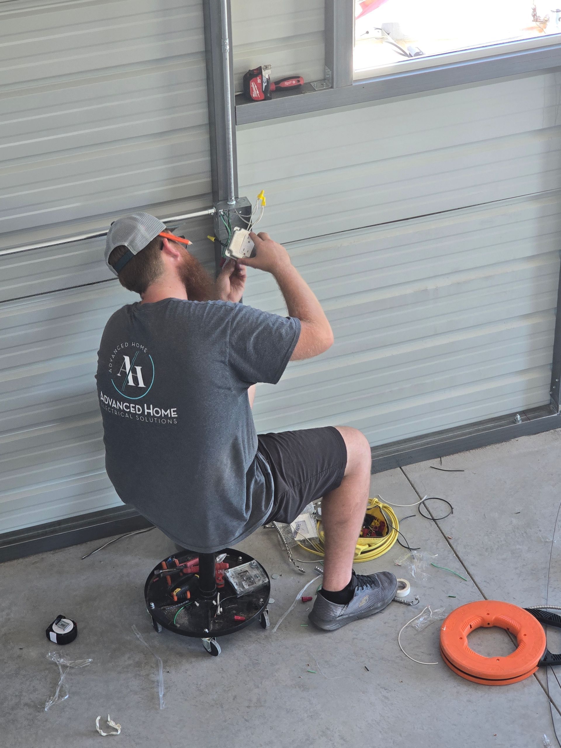 Person in a garage using a drill on a metal door frame, with tools on the floor.