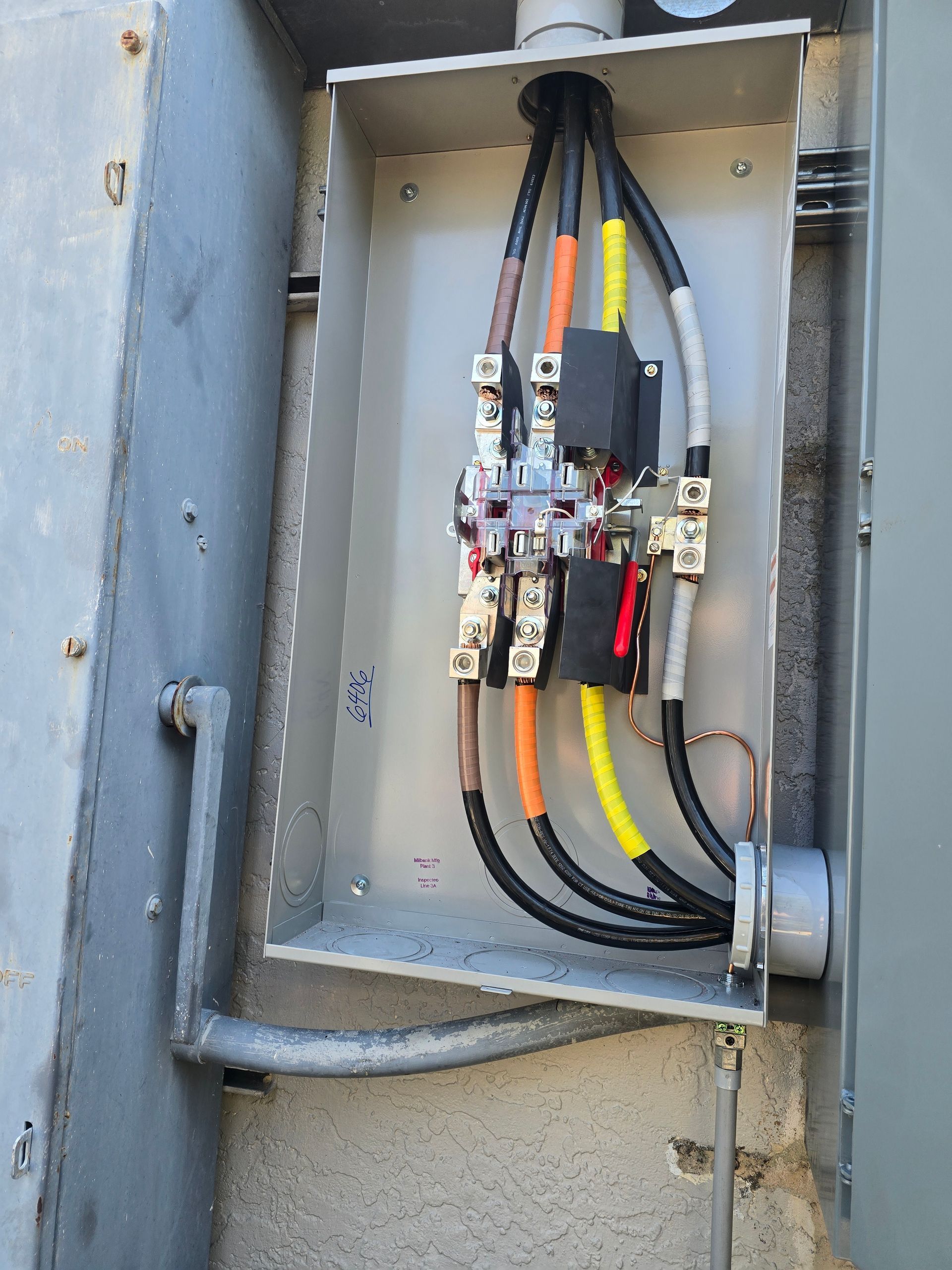 Electrical conduit and thick black, yellow, and red cables inside a gray metal panel box.