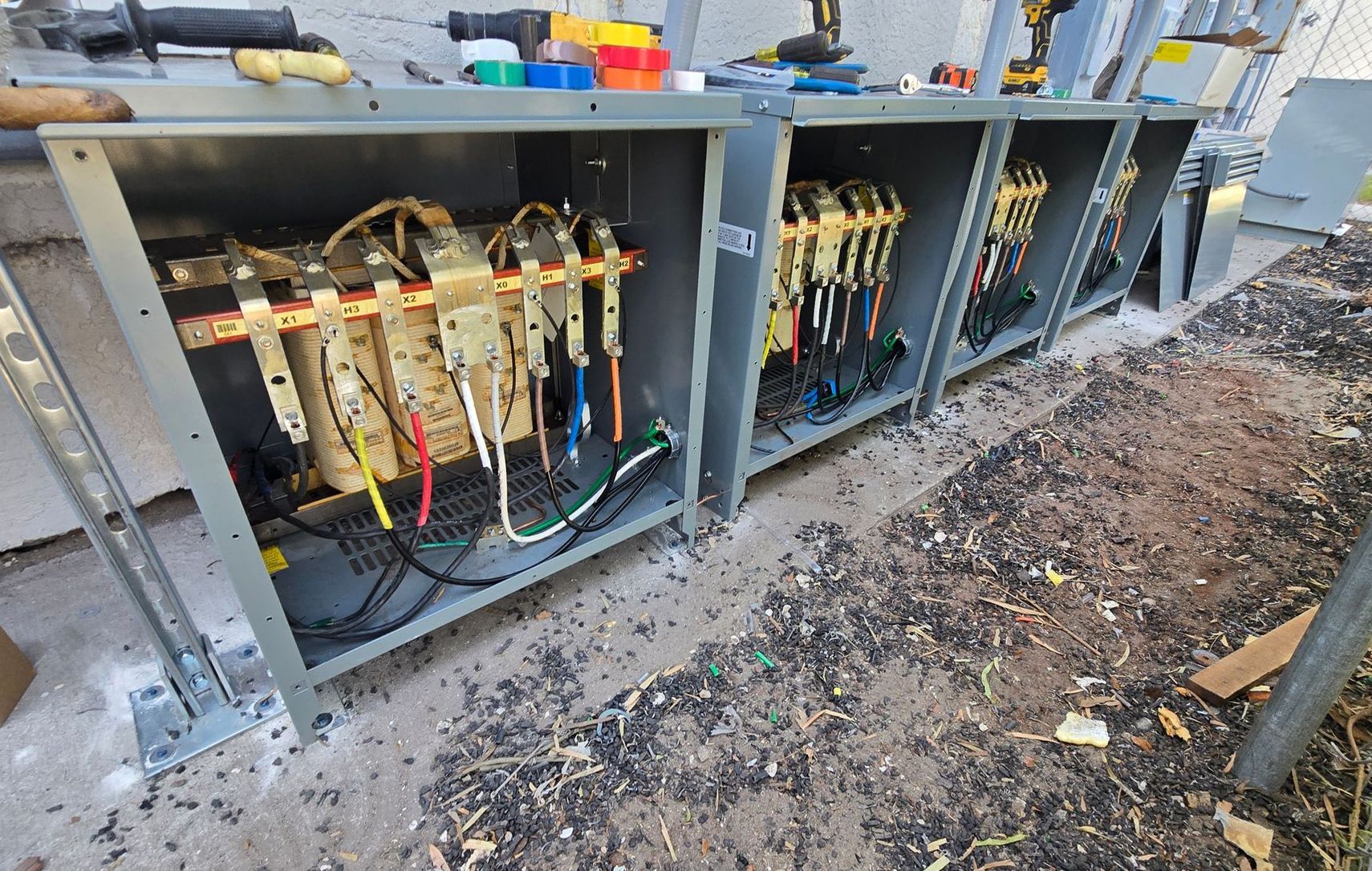 Open electrical control panels with exposed wiring along a gravel roadside.