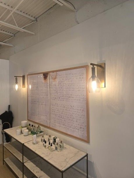 Minimalist vanity with marble sink, lit wall sconces, and a large handwritten board on the wall.