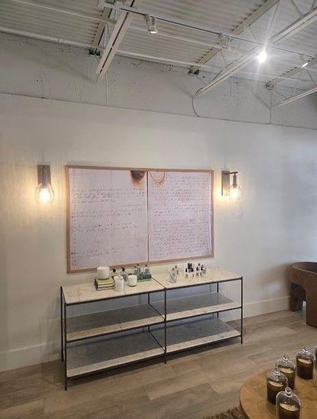 White cafe wall with framed menu boards above a metal shelf and jars on a wooden floor under bright ceiling lights.