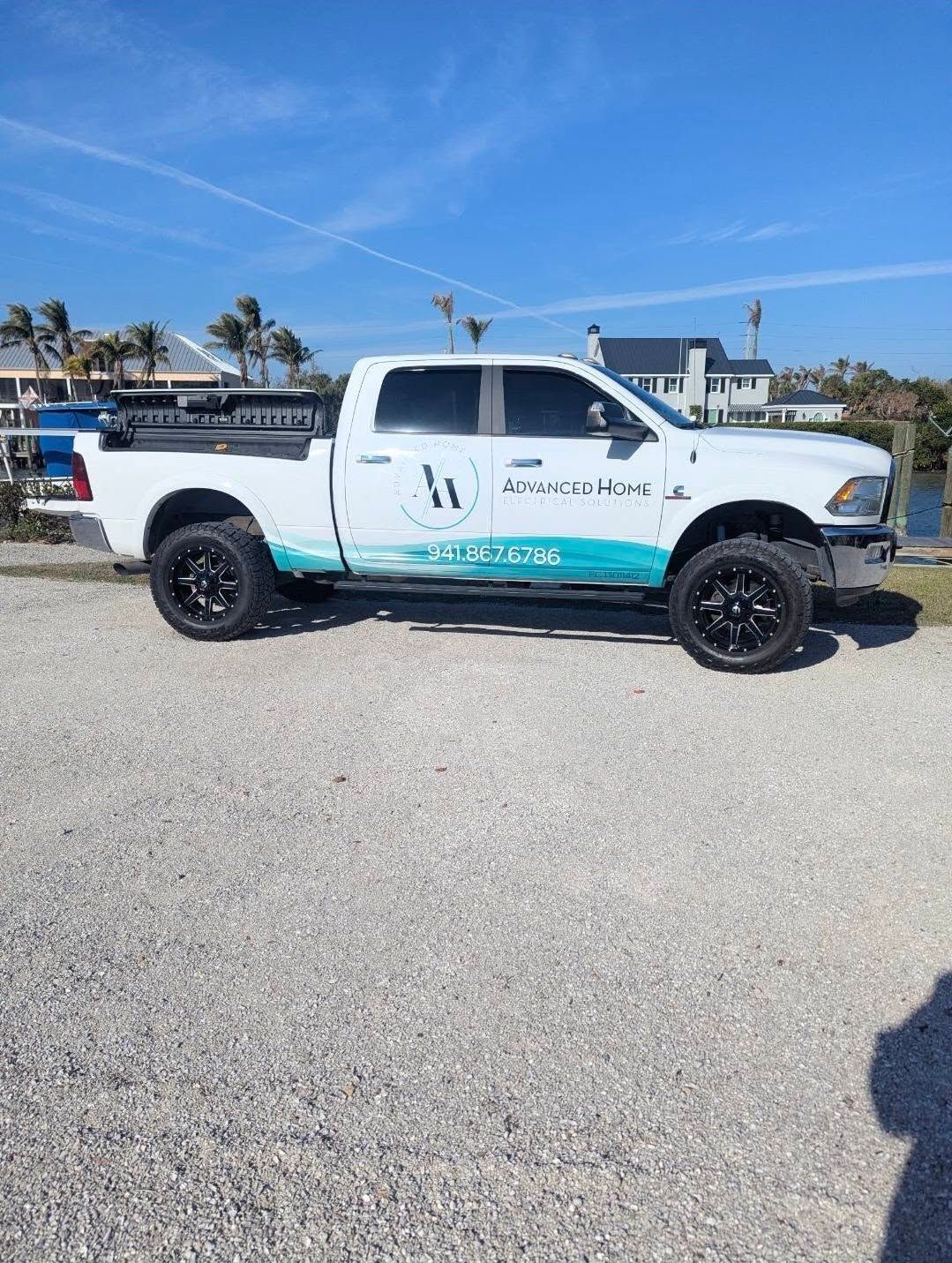 White and turquoise pickup truck parked on gravel near the waterfront under a clear blue sky