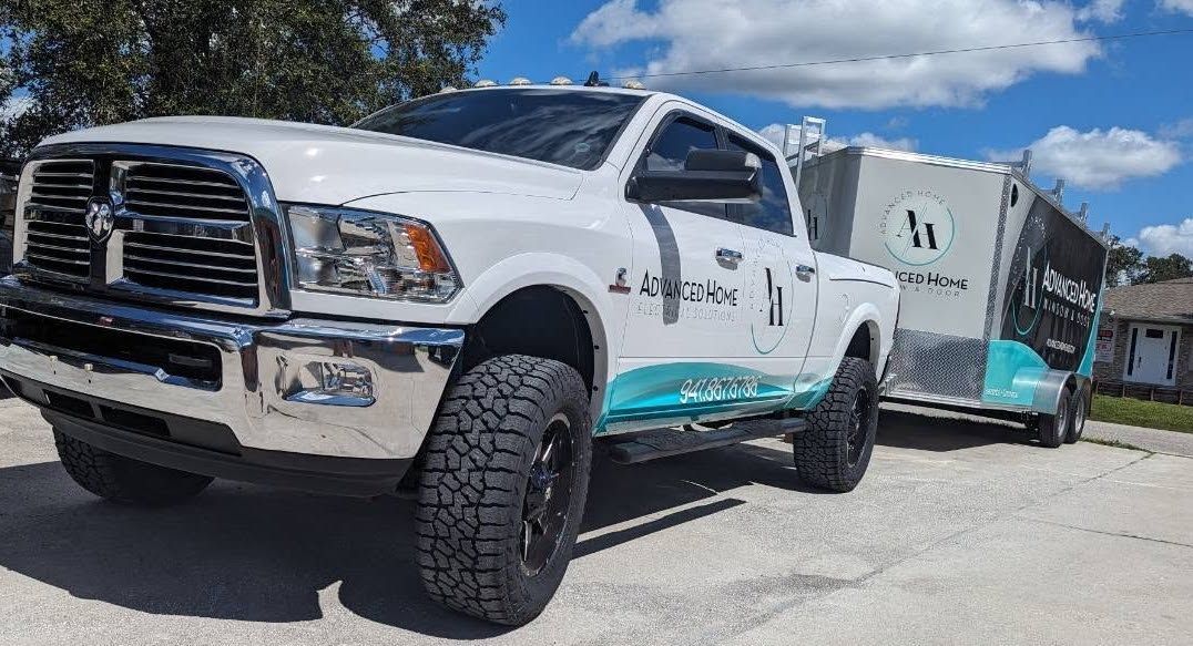 White pickup truck with teal graphics towing a trailer in a sunny parking lot