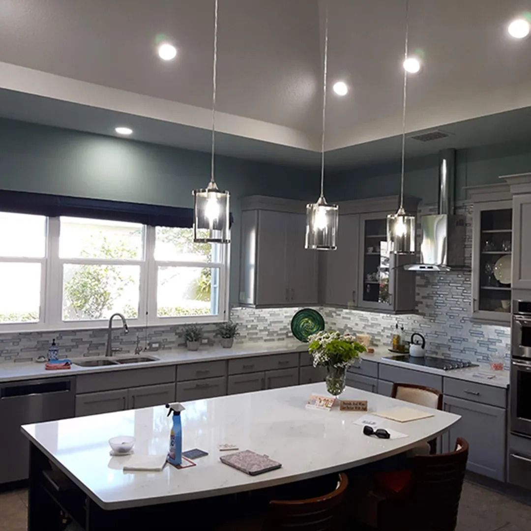 Modern gray kitchen with white island, pendant lights, and flowers on the counter