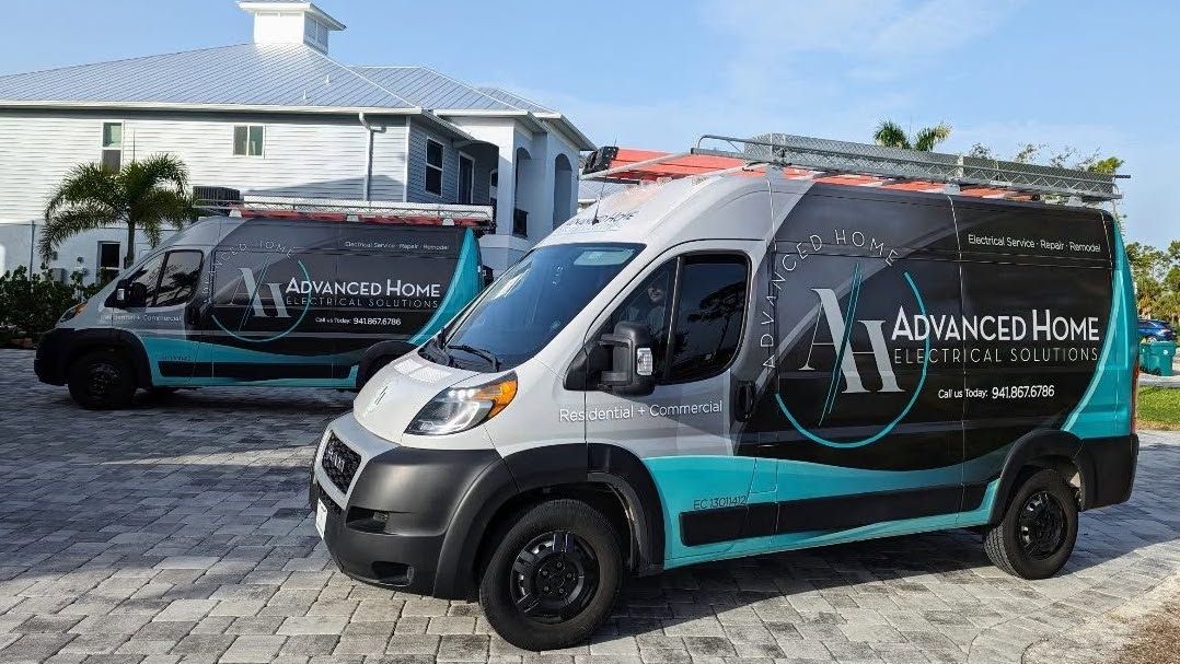 Two black-and-teal branded vans parked outside a white building on a cobblestone lot.