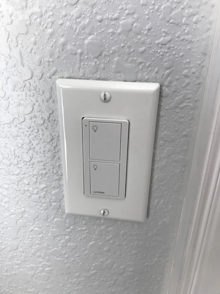 White dual light switch on textured wall with white trim
