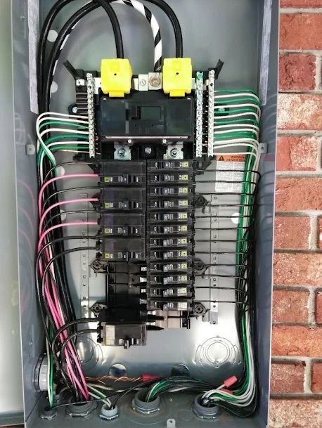 Open electrical breaker panel with wiring and two yellow devices mounted at the top