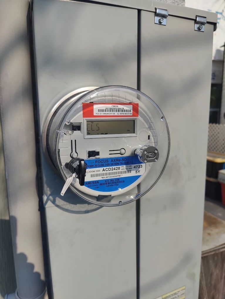Gray utility cabinet with a round meter and red-and-blue labels on the front