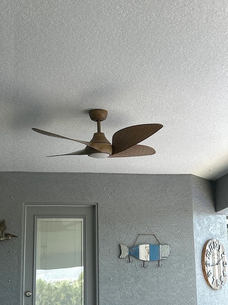 Ceiling fan in a gray room with wall decor and a window shade.