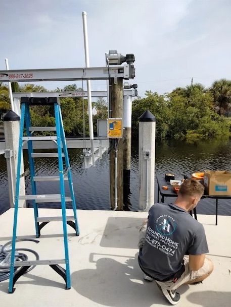 Man on dock beside blue ladder, working near a boat lift over calm water and trees