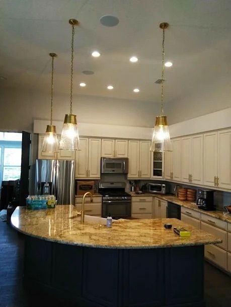 Modern kitchen with granite island, white cabinets, stainless steel appliances, and hanging pendant lights