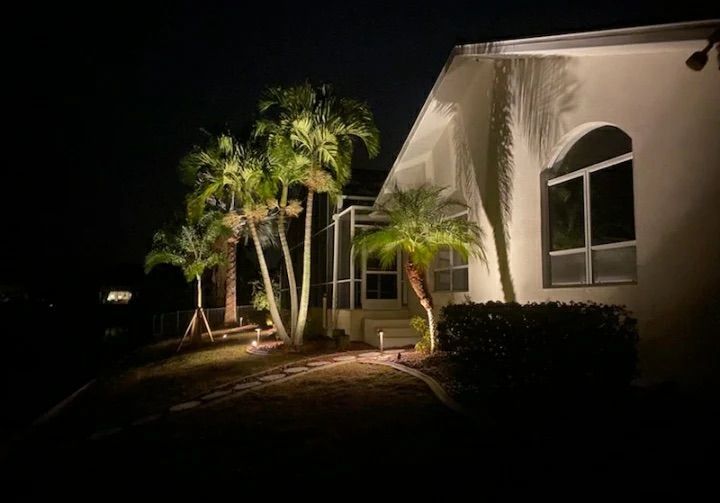 Night-lit white house with palm trees and arched windows along a dark walkway