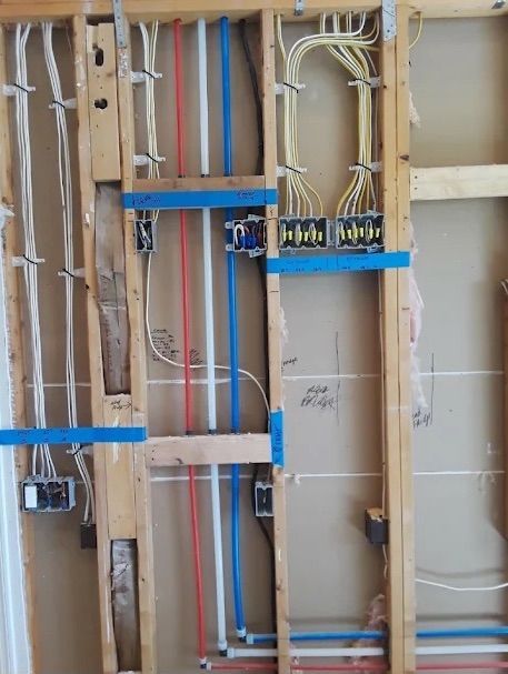 Exposed wall wiring with blue outlet boxes and red, white, and blue cables in a construction frame