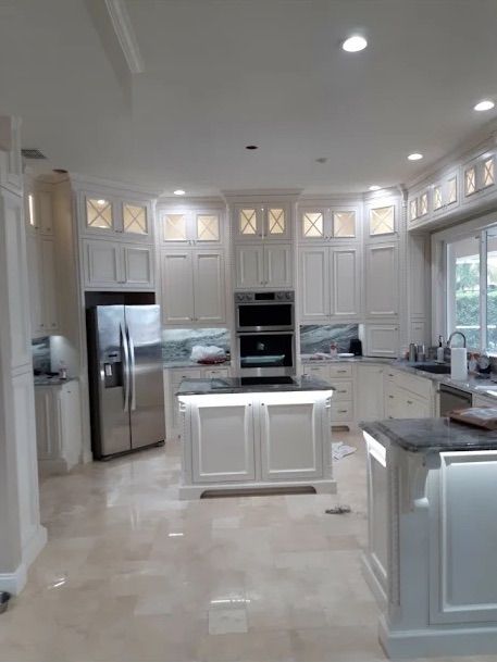 Bright white modern kitchen with stainless steel appliances, island, and large windows