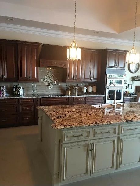 Spacious kitchen with dark wood cabinets, granite island, and hanging pendant light