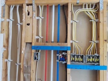 Open electrical wiring in wall studs with blue junction boxes and white, red, and blue cables