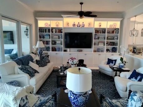 Bright living room with white sofas, navy accents, built-in shelves, and a wall-mounted TV.