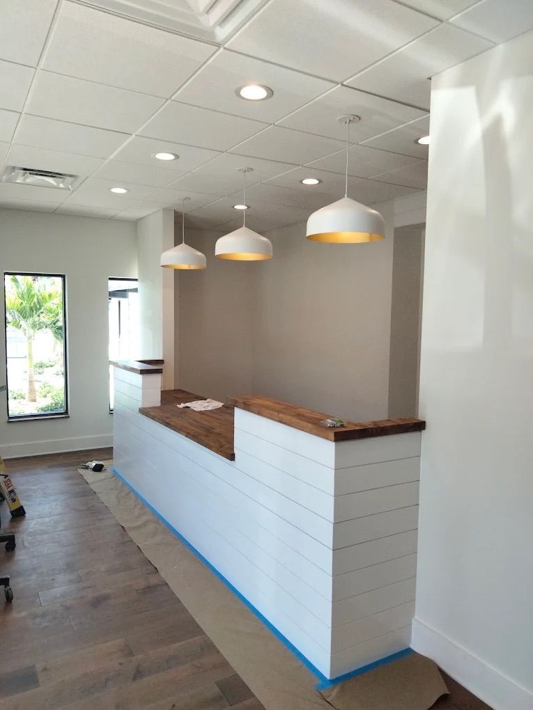 Empty modern reception desk in a bright hallway with pendant lights and wood flooring