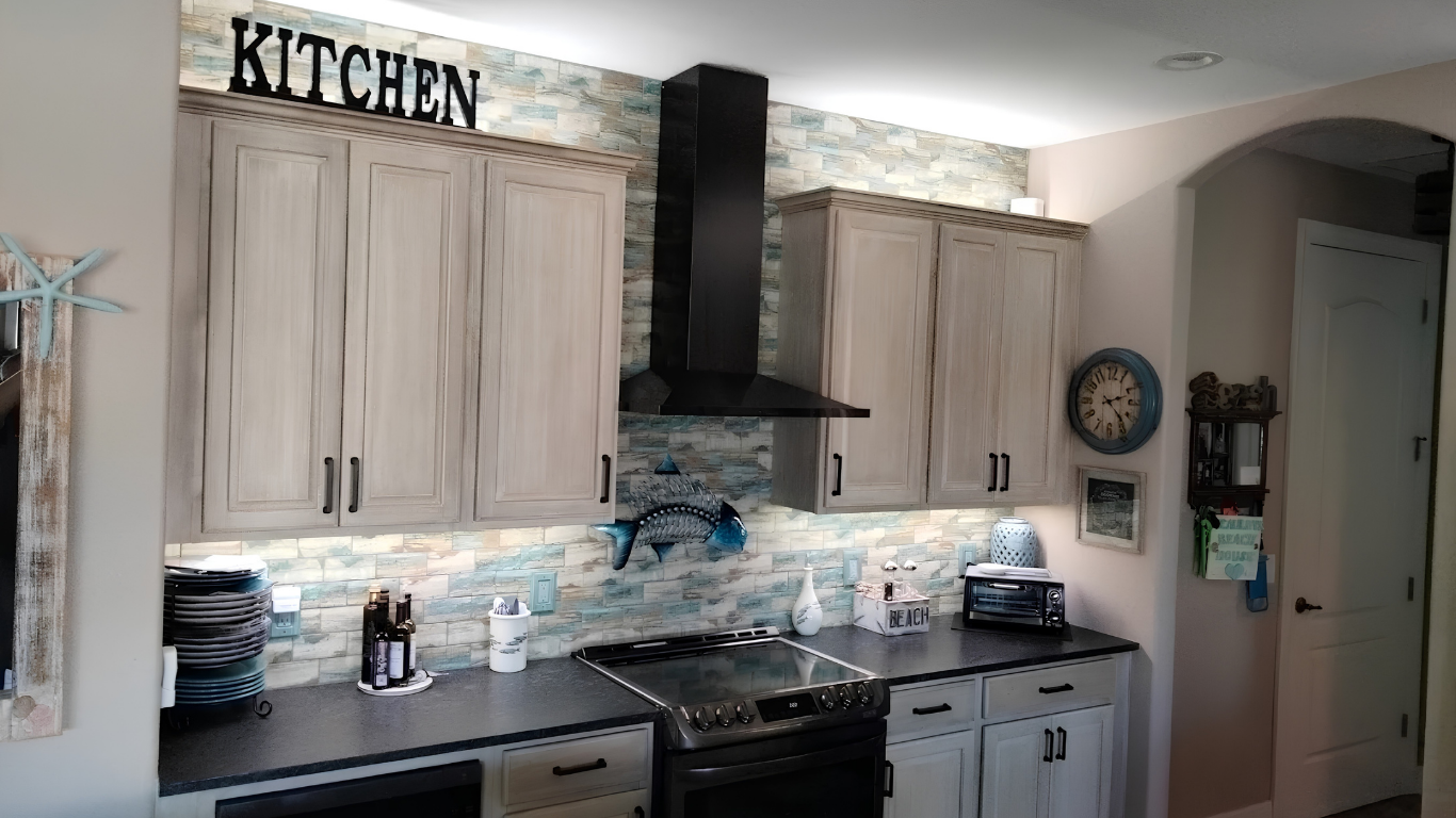 Bright kitchen with light wood cabinets, black range hood, and a decorative backsplash.
