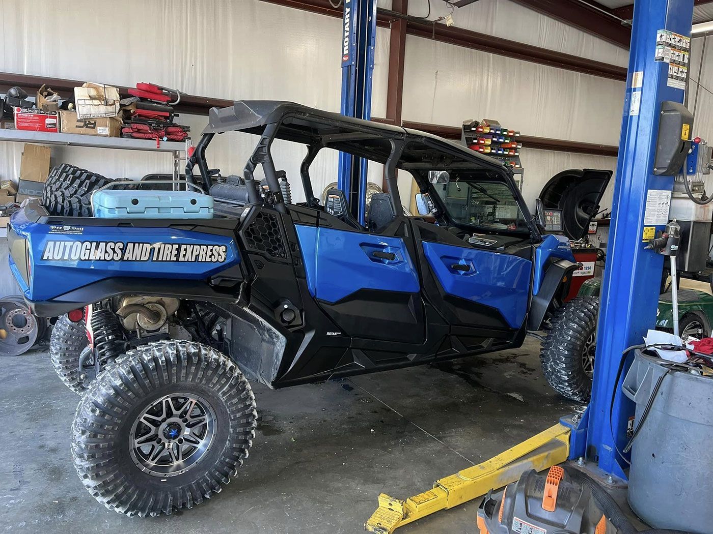 A blue atv is parked on a lift in a garage.IMAGE+PLACEHOLDER