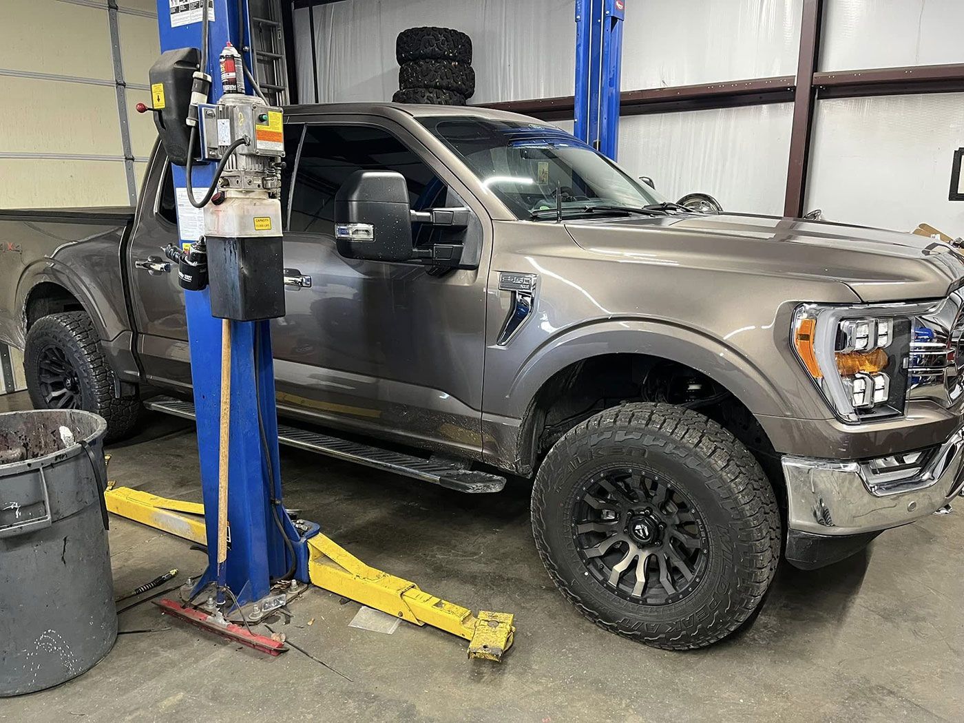 A truck is parked on a lift in a garage.