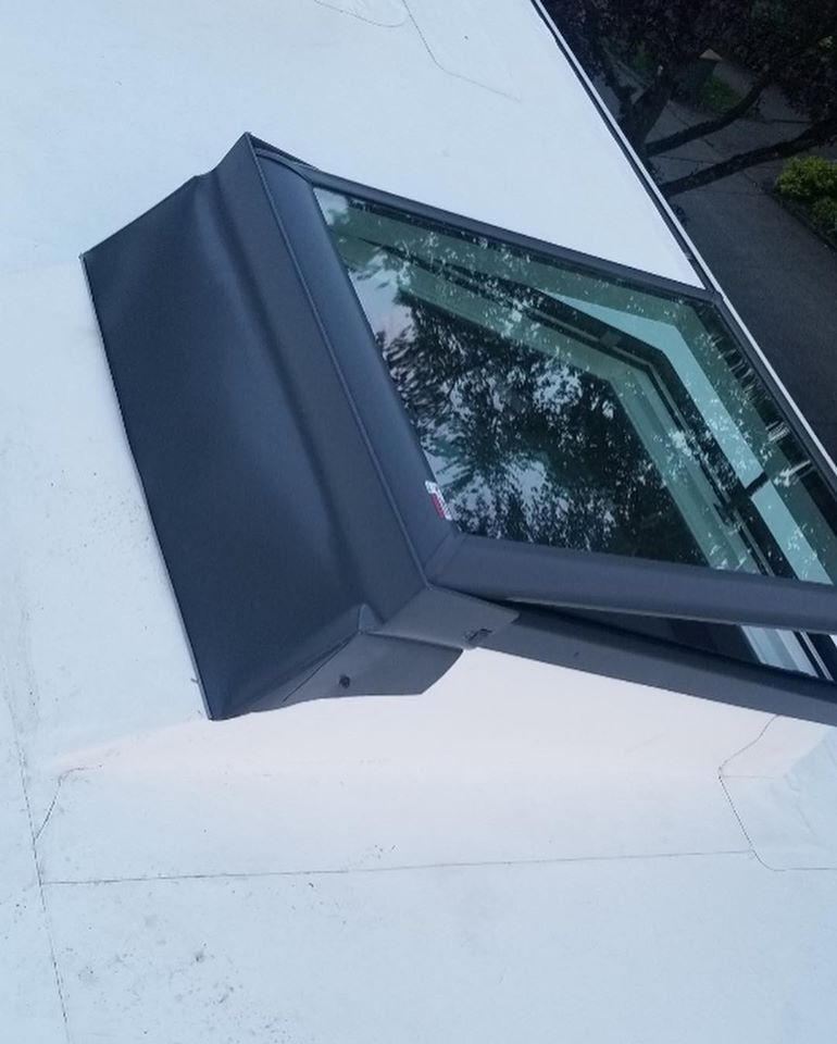 Angled rooftop skylight with dark trim and reflective glass.