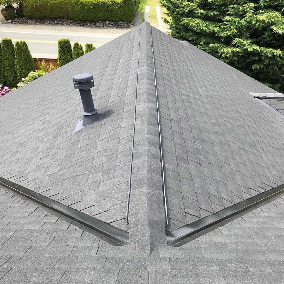 Gray asphalt shingle roof with a vent pipe and angled seams.