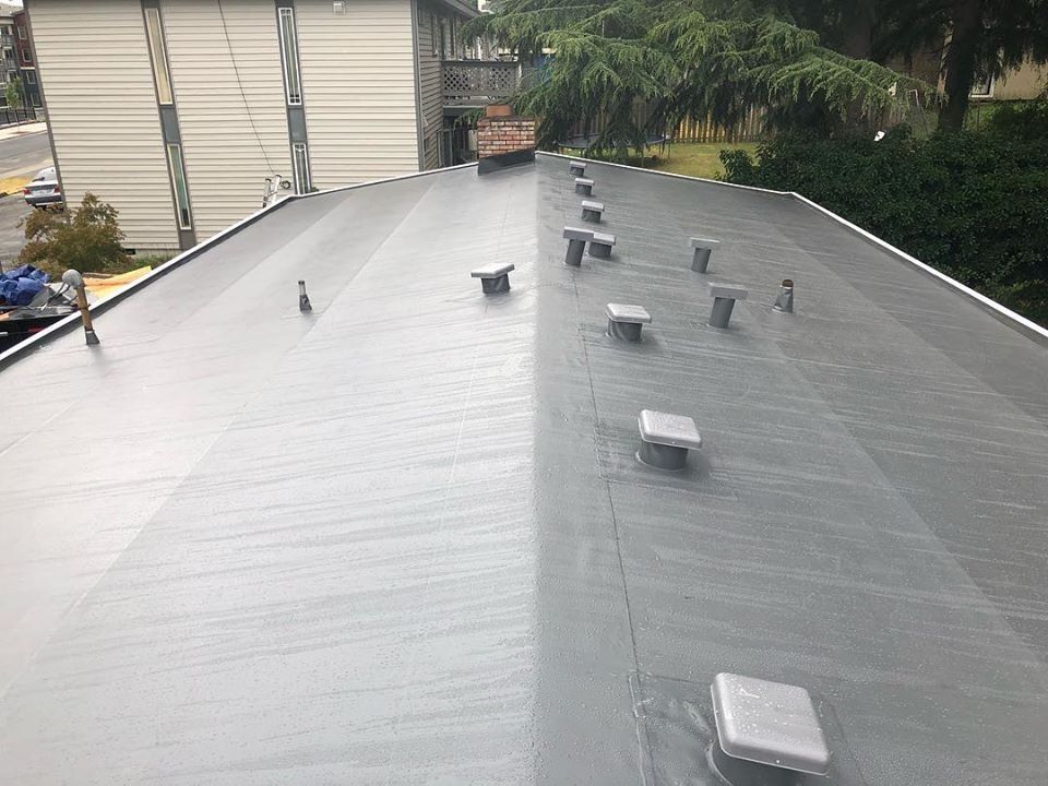 Flat roof with vents. Dark gray surface, residential setting.