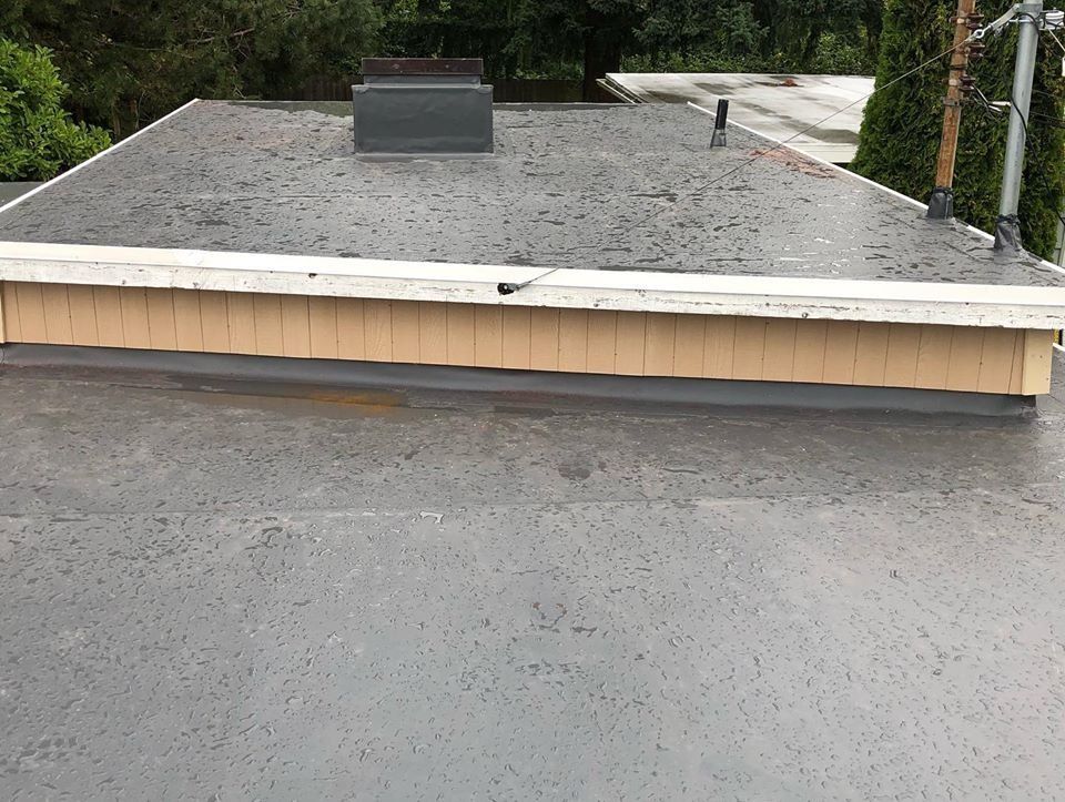 Flat, gray rooftop with a chimney, tan trim, and a slight rain.