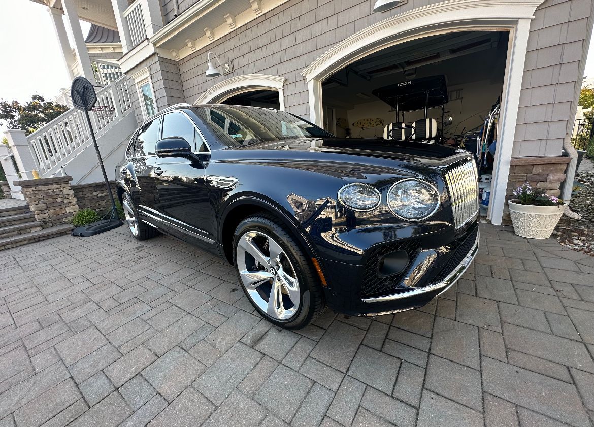 a black Bentley is parked in front of a garage