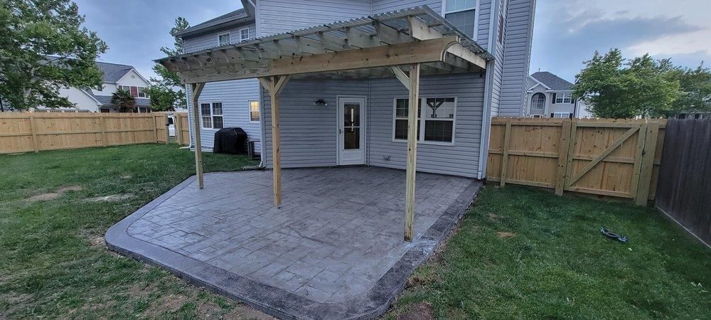 A patio with a pergola in the backyard of a house.