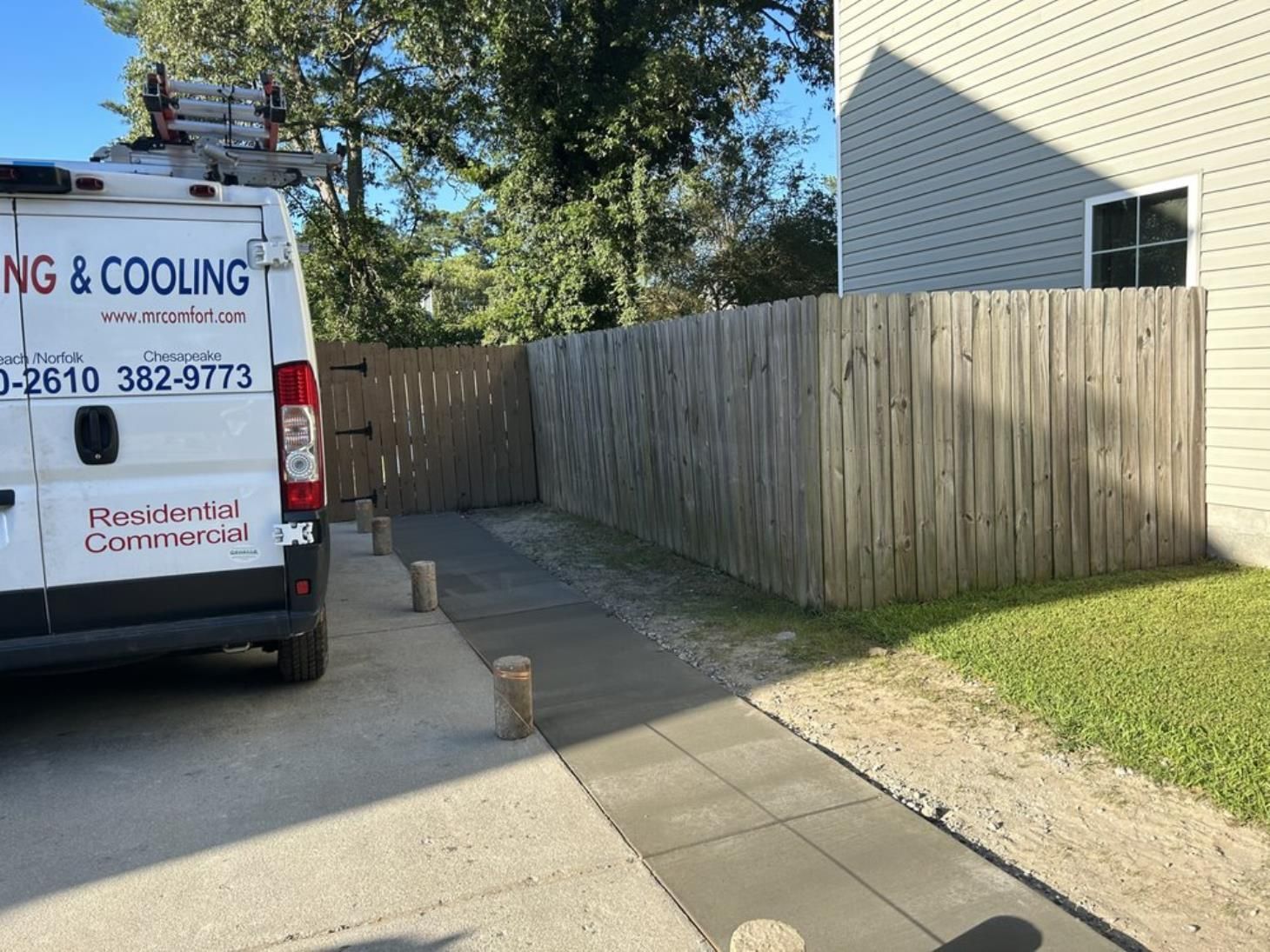 A van is parked in a driveway next to a wooden fence.